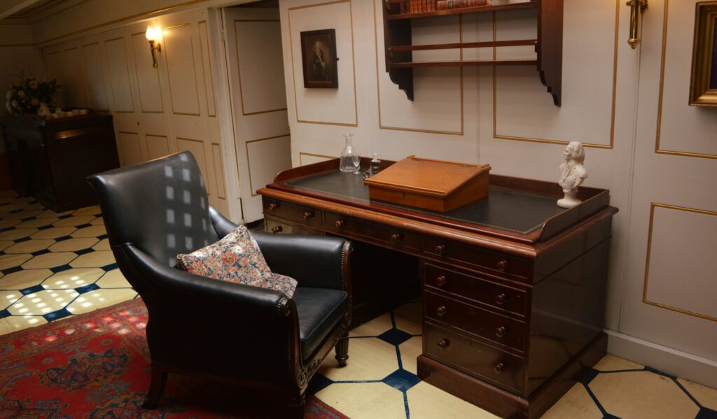 A classic private study with a wooden desk and leather armchair, illustrating the personal assistant role
