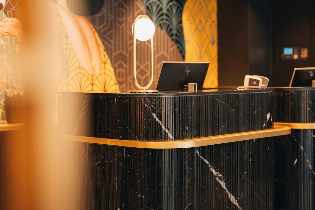 A black marble reception desk with gold trim, representing the external concierge service model