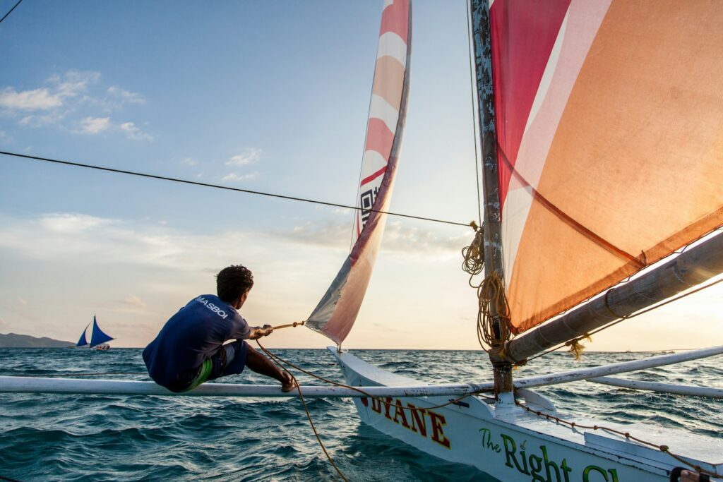 A sailor racing a small boat under a colourful spinnaker