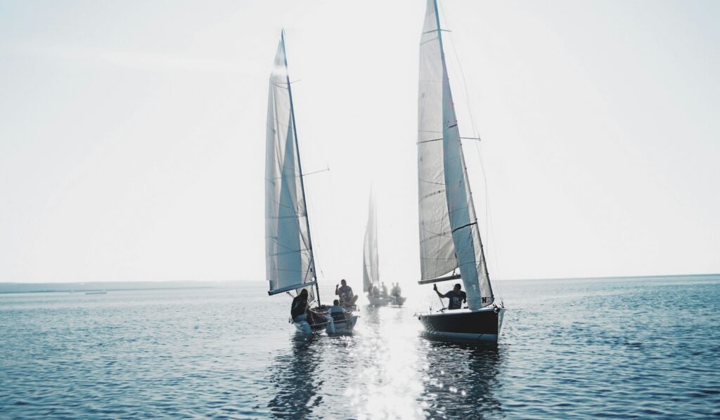 Two sailing yachts racing on open water, one ahead of the other