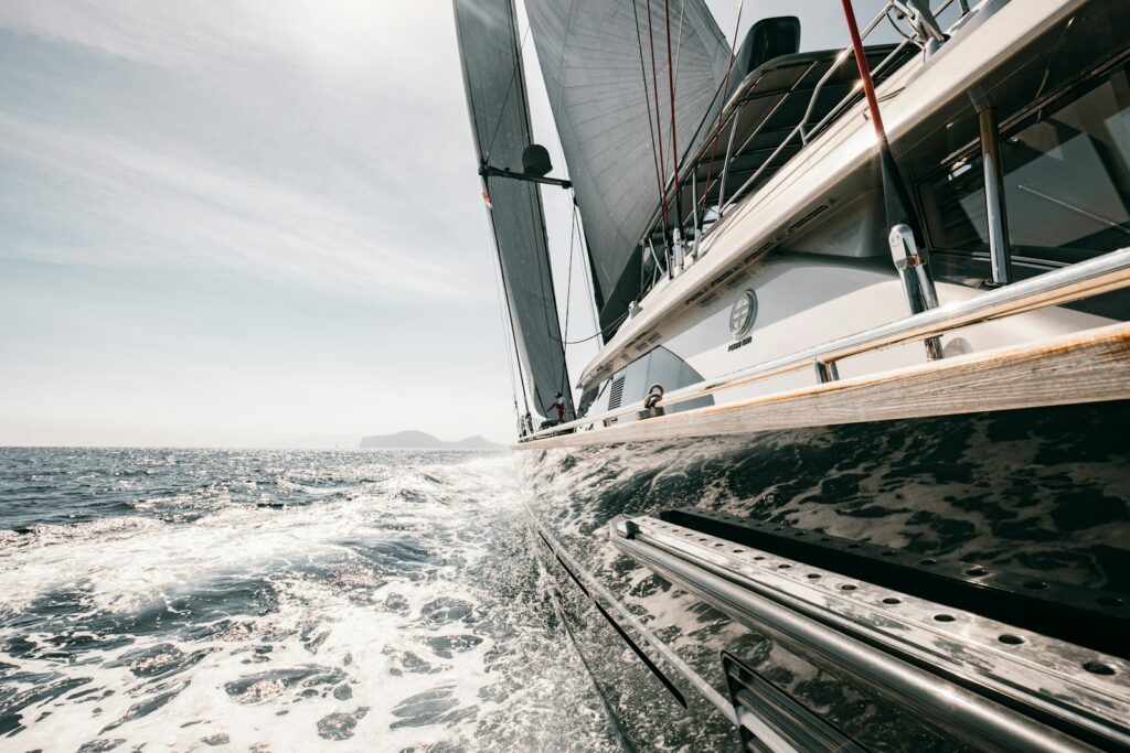 A sailing yacht heeled over in open water, spray breaking across the deck