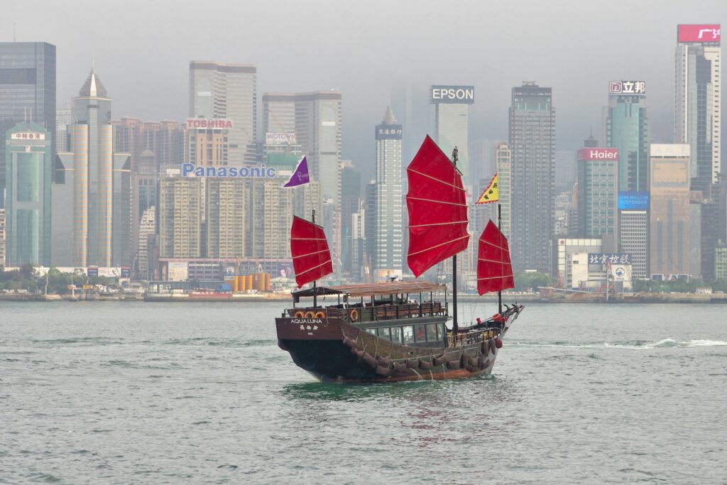 A traditional junk boat with red sails crossing Victoria Harbour, Hong Kong