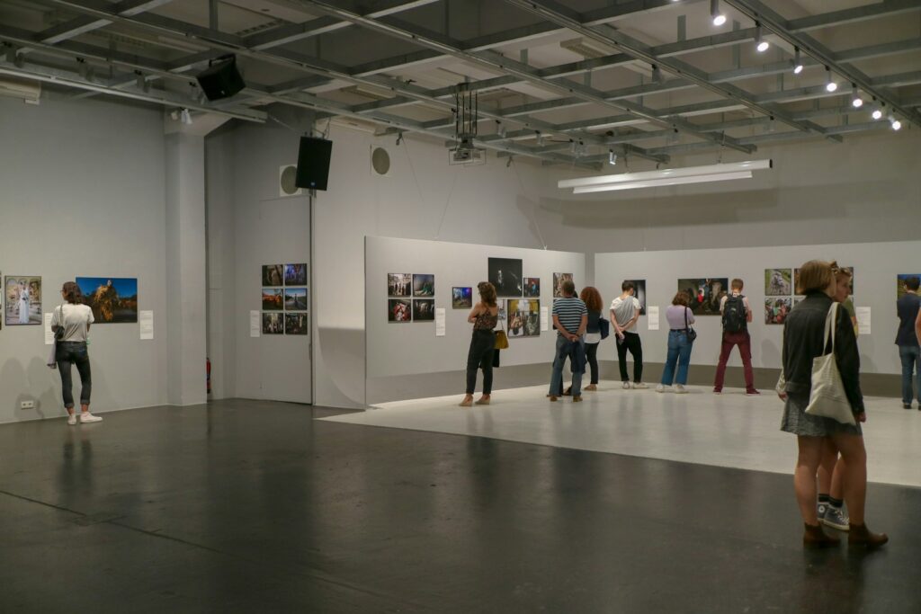 Visitors walking past contemporary artworks on display in a gallery space