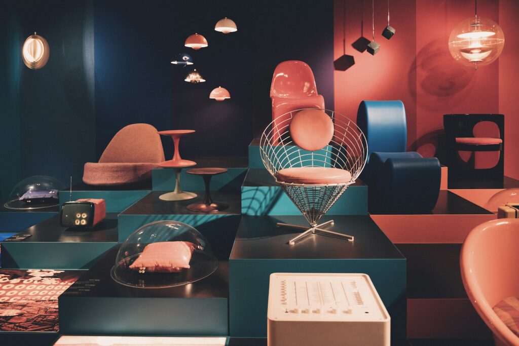 Mid-century modern chairs and pendant lighting arranged on tiered gallery plinths