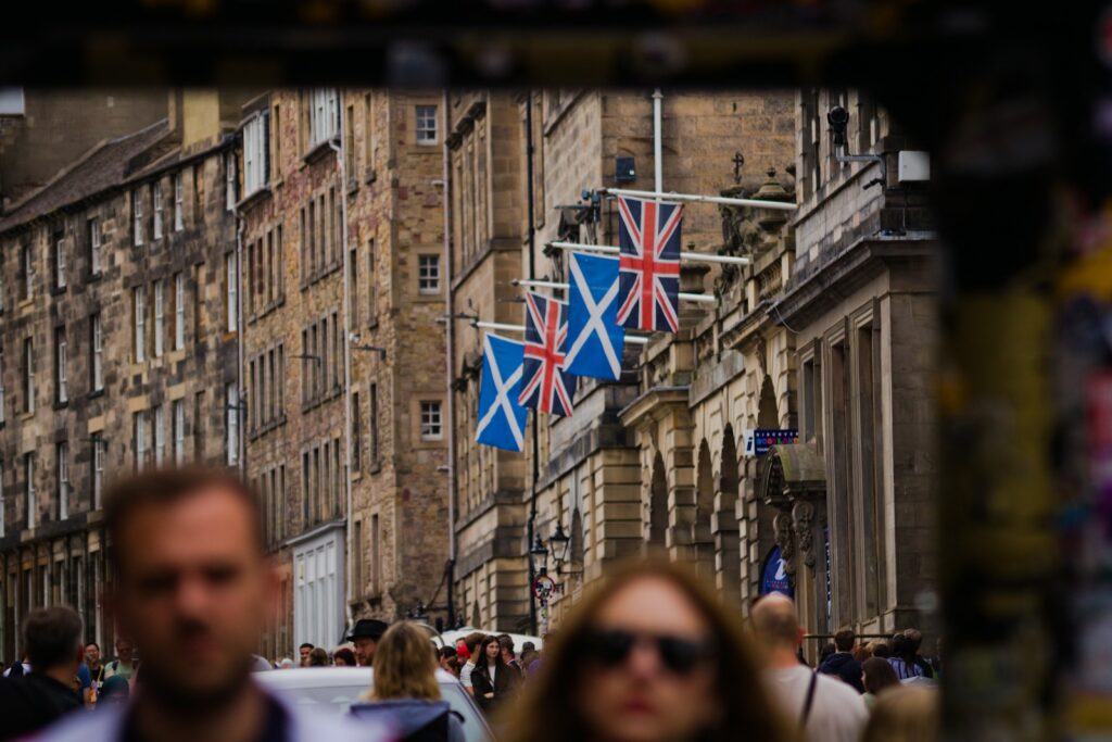 Saltire and Union flags lining a historic stone street in Edinburgh's Old Town