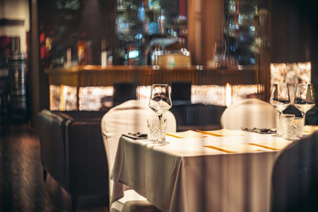 A quiet dining room laid for service, where most bookings never appear under the client’s own name