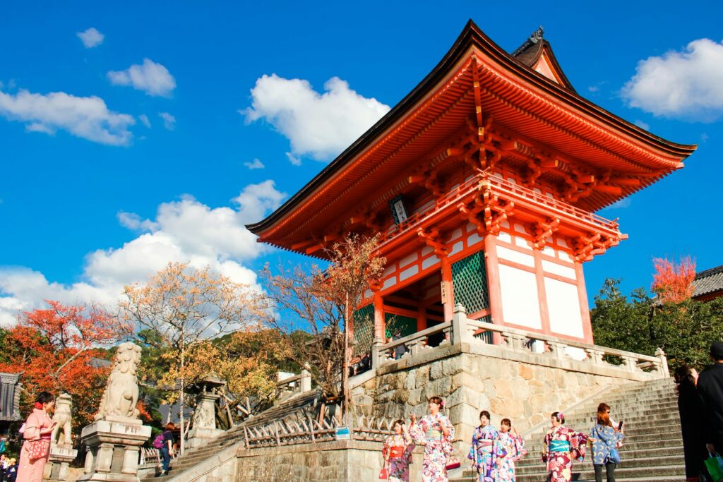 A vermilion temple gate under cherry blossom in Japan in spring
