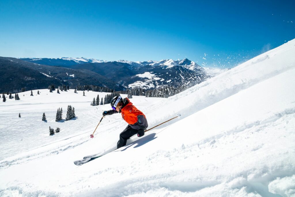 Downhill skier carving a turn on a groomed alpine slope