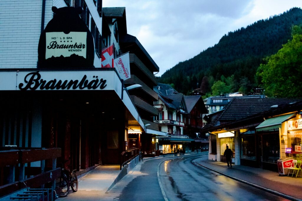 Evening in the car-free village street of Wengen with hotel and shop signs lit
