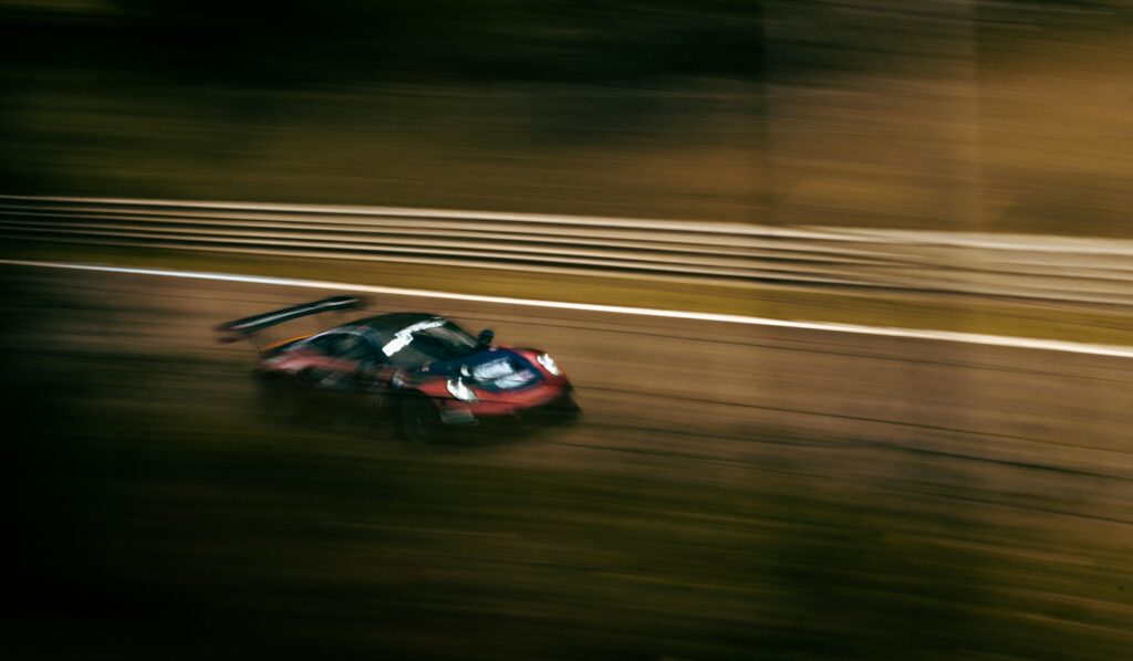 Racing car at speed under floodlights during the night at Le Mans — Perfect.Live