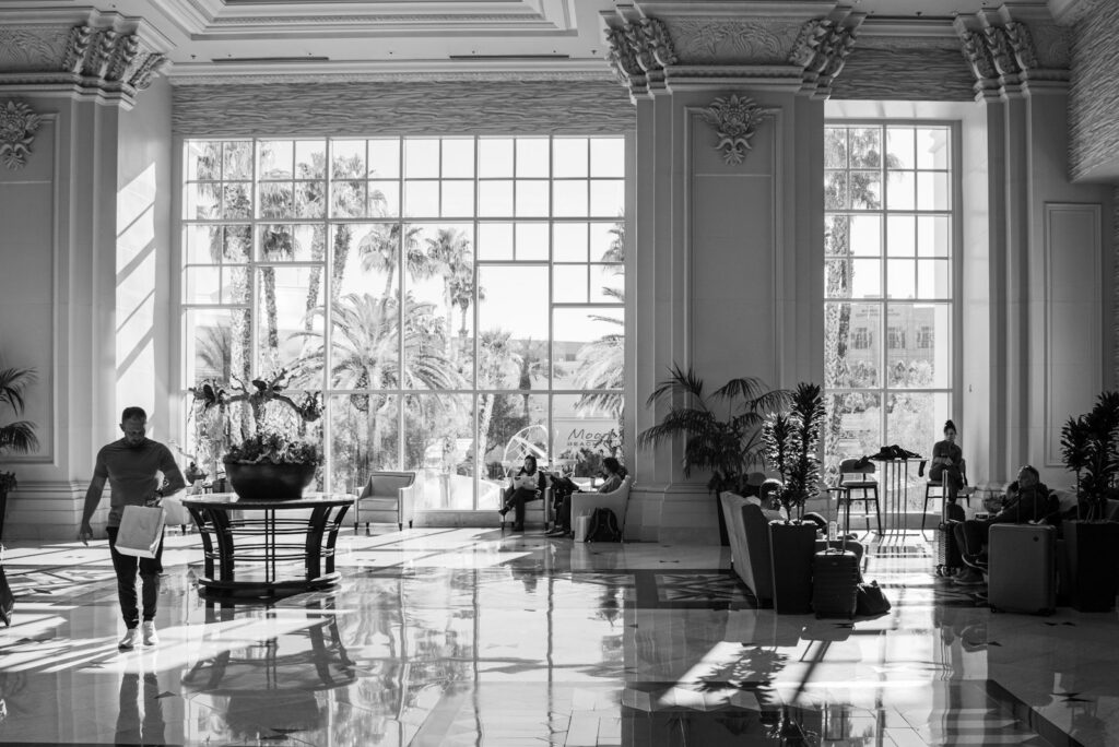 A grand hotel lobby in black and white, staff crossing the floor at a distance