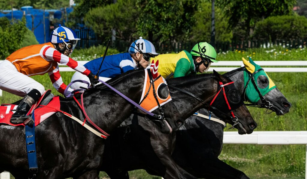 Jockeys in colourful silks driving their horses through a turn during a flat handicap race