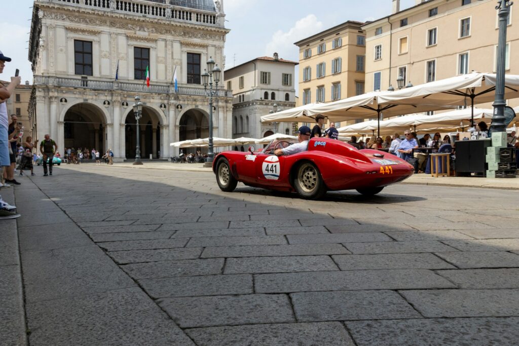 Vintage race car on a cobblestone street in a historic Italian town during the Mille Miglia