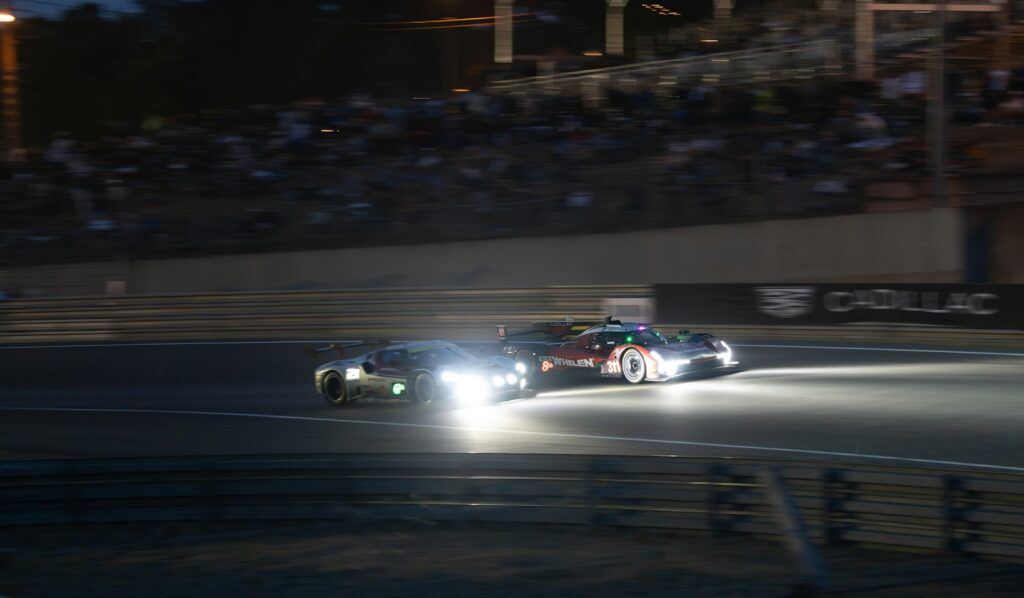 Sports cars racing at night under floodlights at the Rolex 24 at Daytona