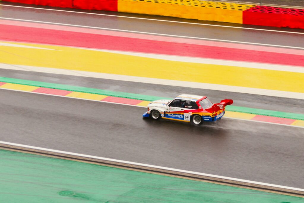 Aerial view of a GT car taking the Eau Rouge kerb at Spa-Francorchamps