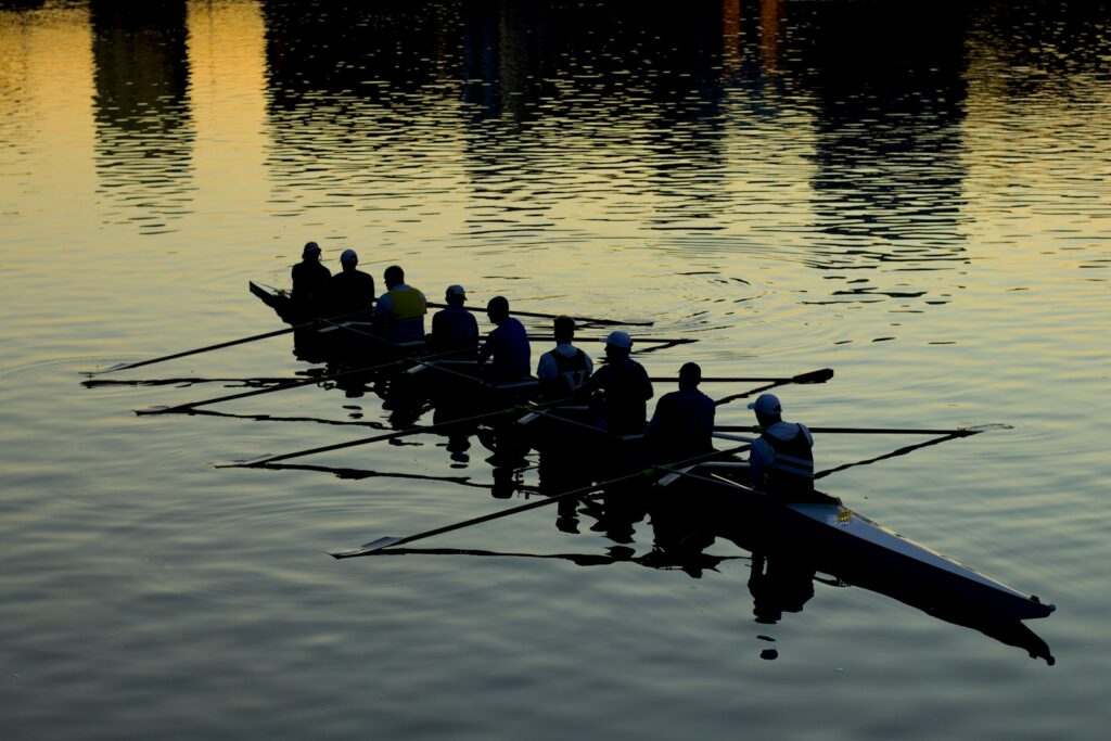 Silhouette of a rowing eight training on the water at dusk