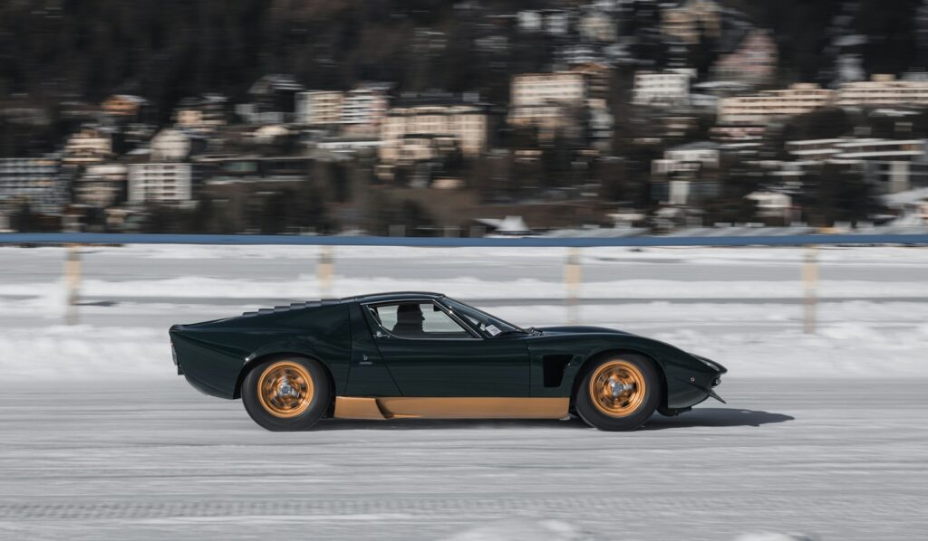 Classic sports car driven across the frozen lake at The Ice St Moritz with the town behind