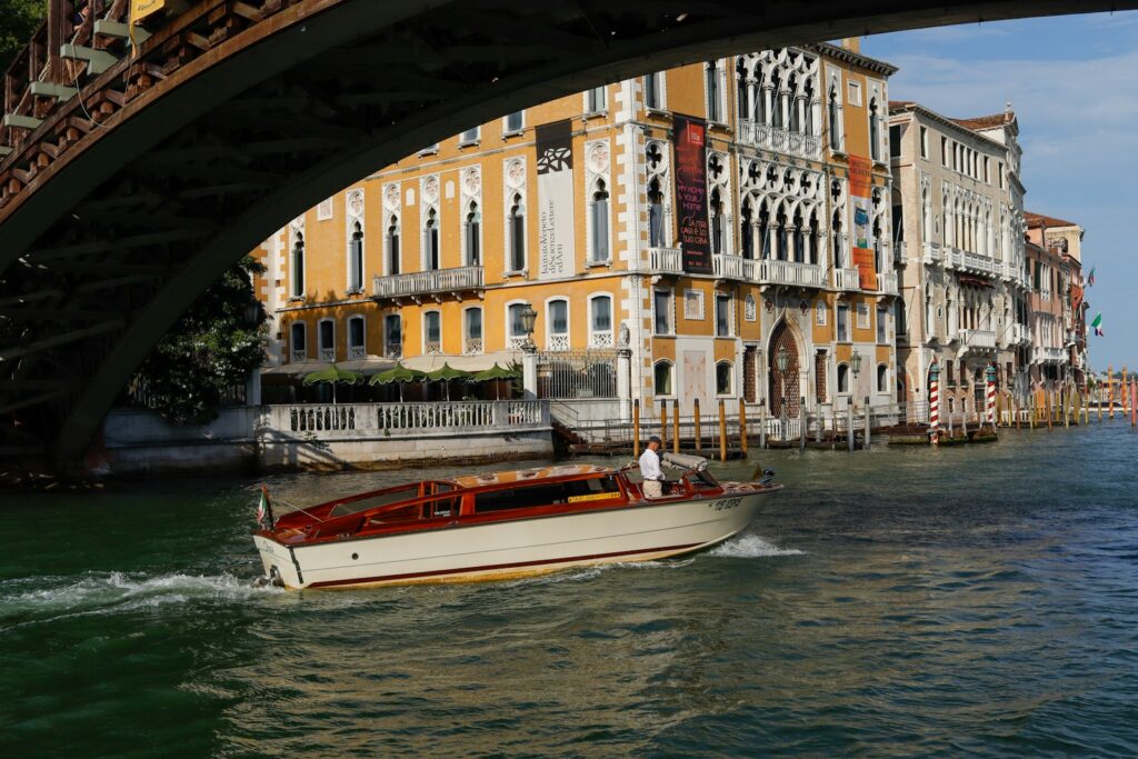 A water taxi passing beneath a bridge on a canal in Venice