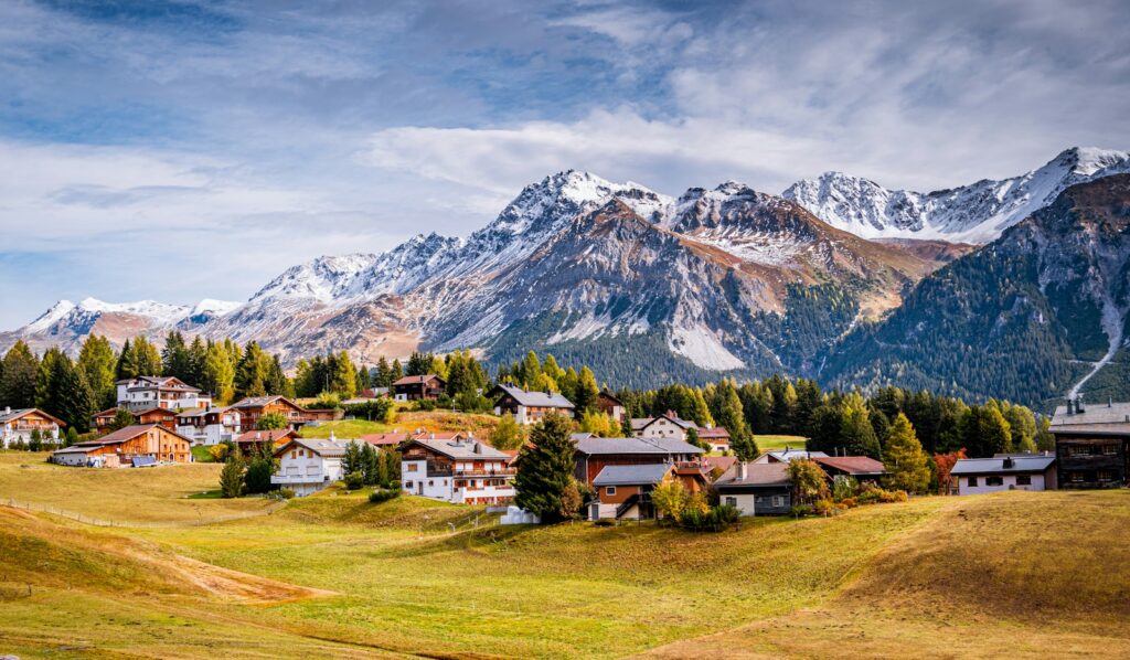 Alpine village on a green meadow below snow-capped peaks in the Swiss Valais near Verbier