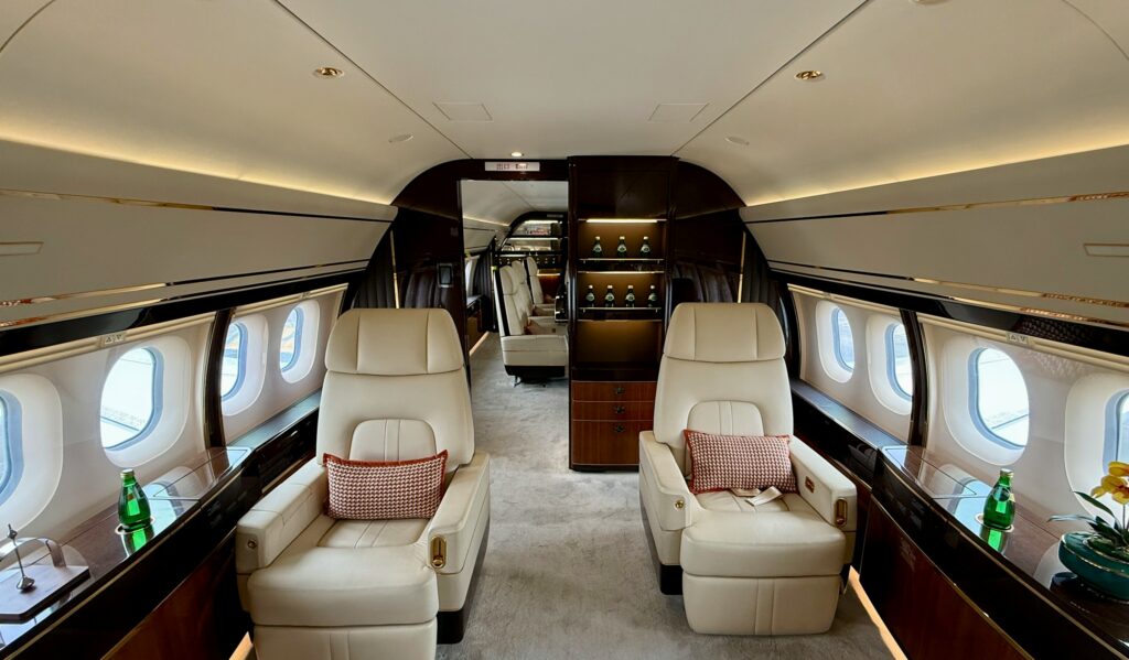Ultra-high-net-worth individual — the quiet cabin of a private jet, seats turned toward each other