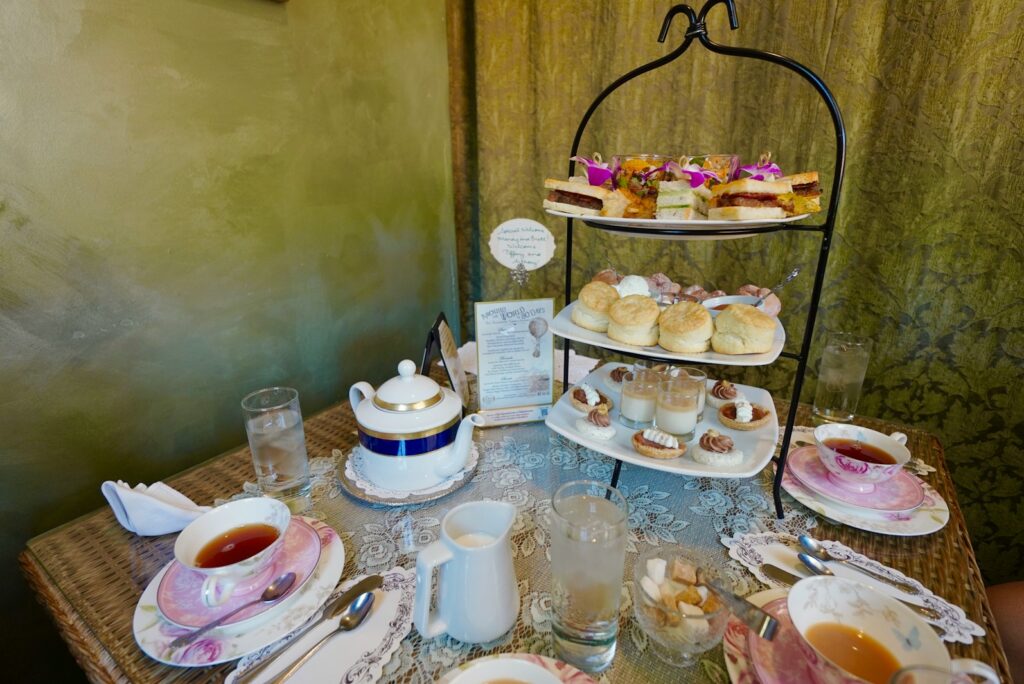 Afternoon tea table with a tiered stand, teapot and cups in an elegant hotel room