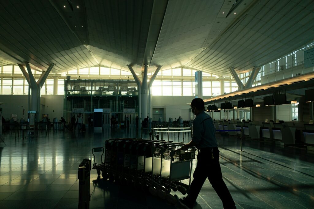 A traveller with a luggage cart in a bright airport terminal