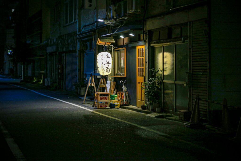 Quiet Tokyo side street at night with a paper lantern outside a small restaurant