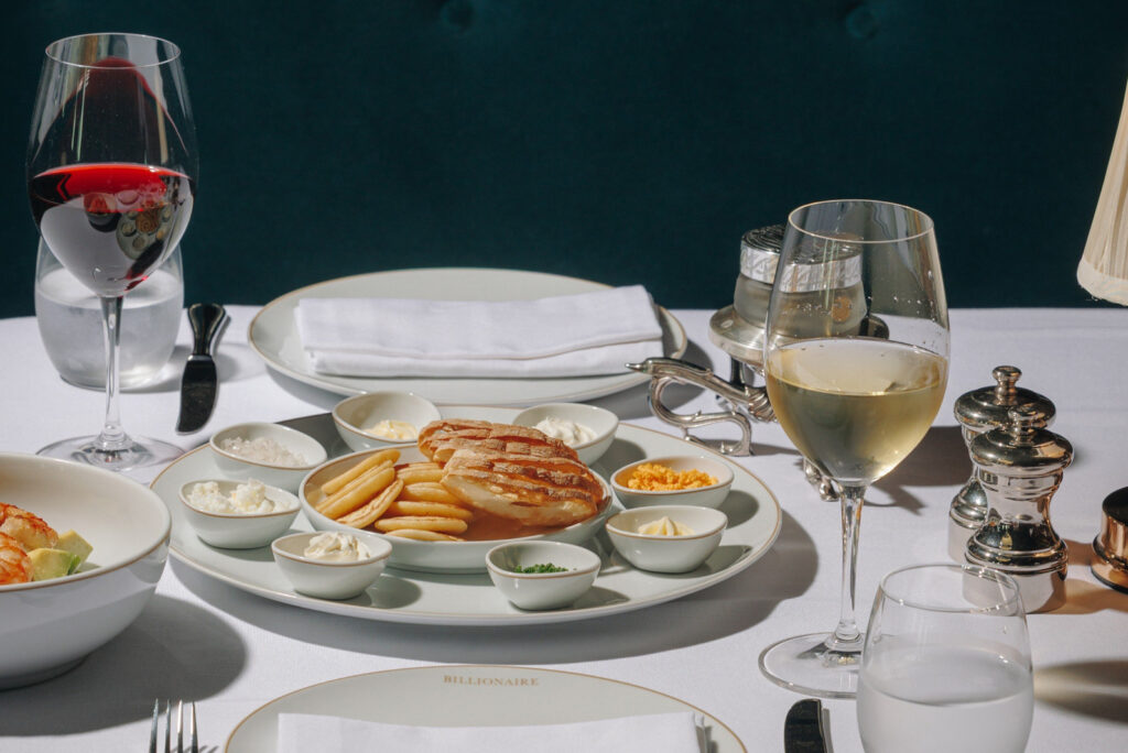 Table setting with wine glasses and sharing plates at Billionaire Dubai