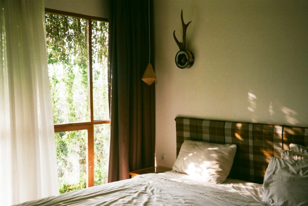 Bedroom with a plaid headboard and morning light falling across white linen