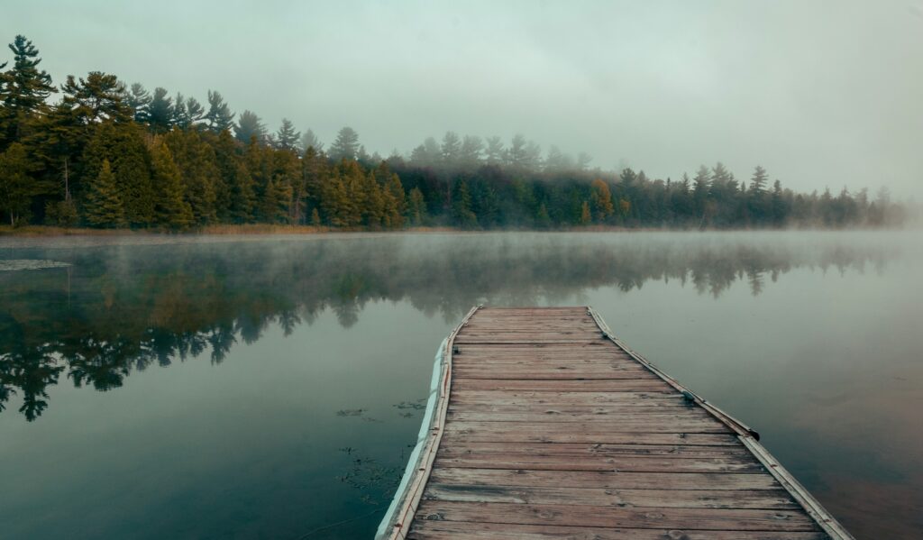 Burnout recovery for a leader: a quiet wooden jetty on a misty lake at a private retreat
