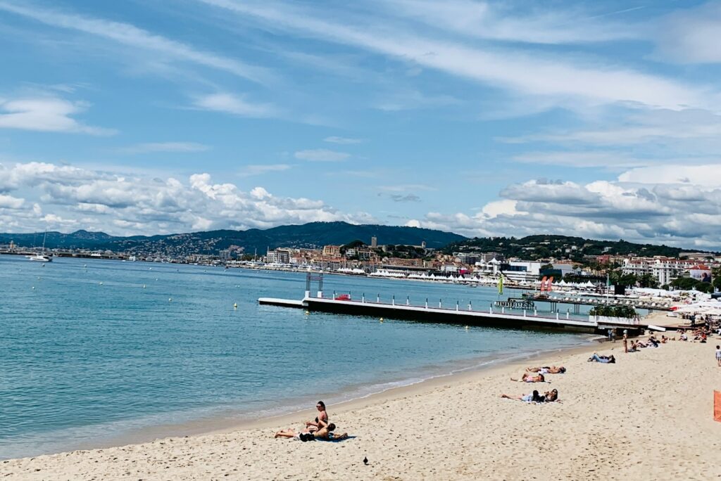 Sandy beach and a pontoon on the Cannes seafront under a blue sky