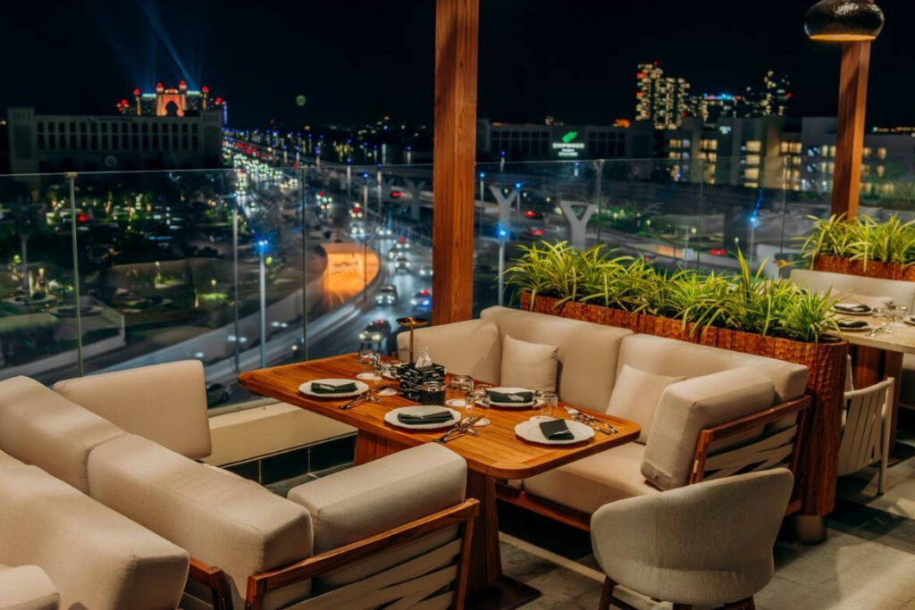Terrace table at Chalet Berezka Dubai at night with city lights beyond the glass