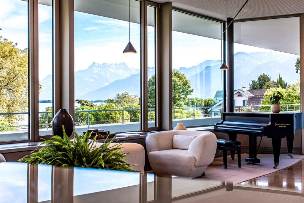 A lounge at Clinique La Prairie in Montreux with floor-to-ceiling windows onto Lake Geneva and the Alps