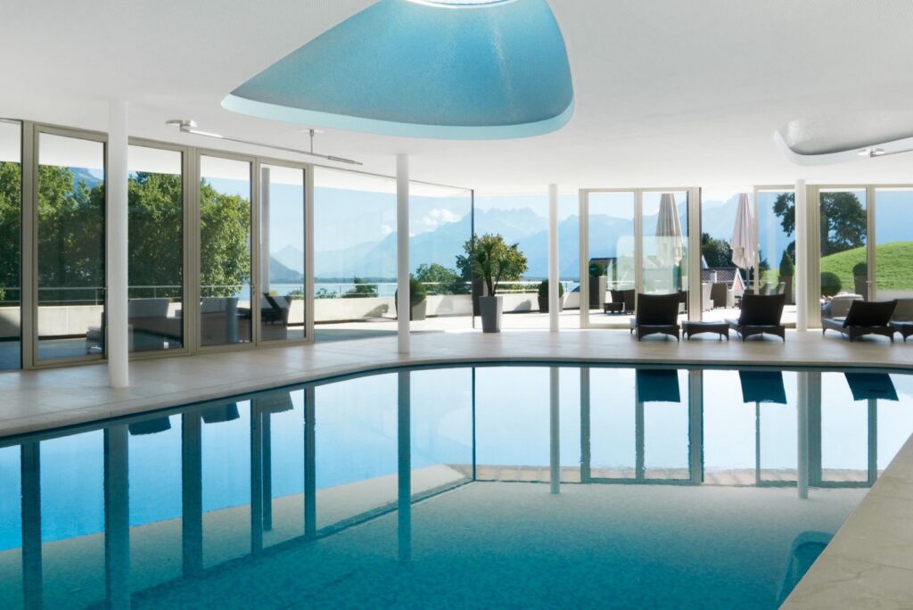 The indoor swimming pool at Clinique La Prairie in Montreux, opening onto a terrace with views of the Alps
