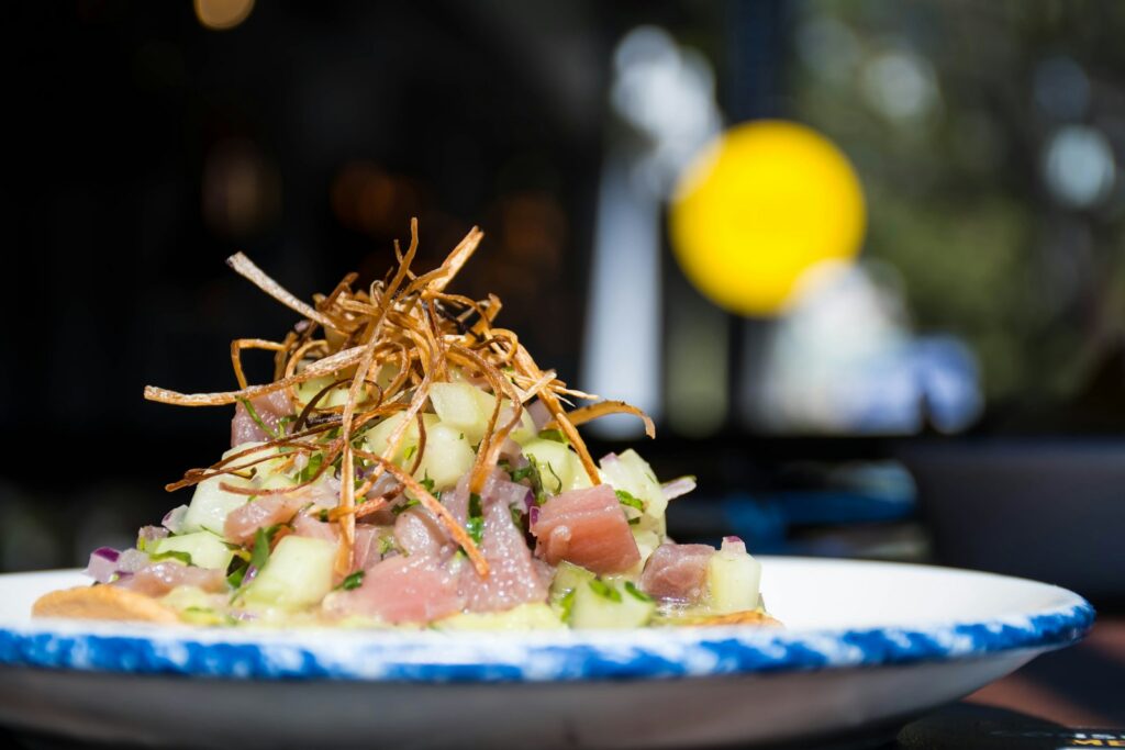 A tuna tiradito dish with crispy garnish, plated at a Peruvian restaurant