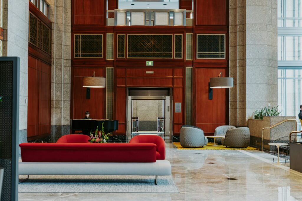 Hotel lobby with a red sofa and marble floor beneath a tall panelled wall.
