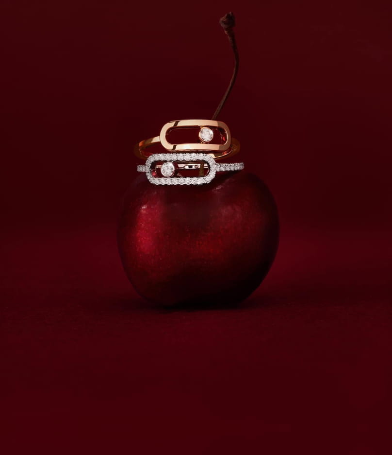 Diamond rings resting on a dark red cherry