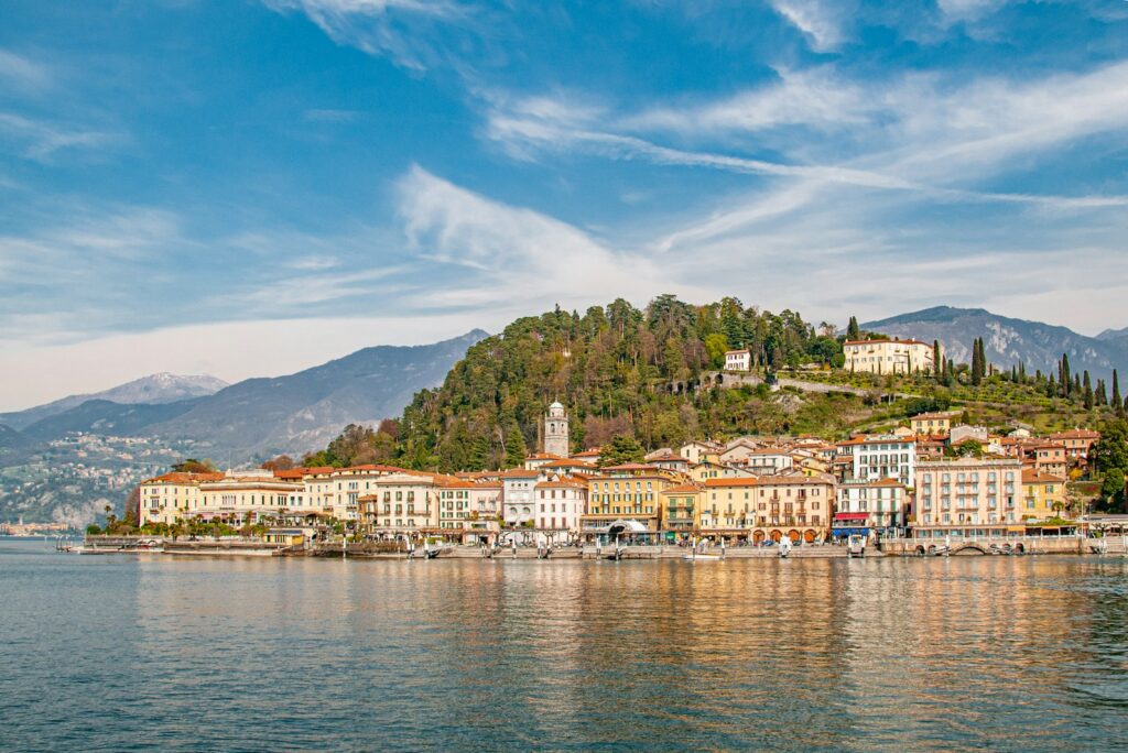 Pastel waterfront houses beneath a wooded hill on Lake Como