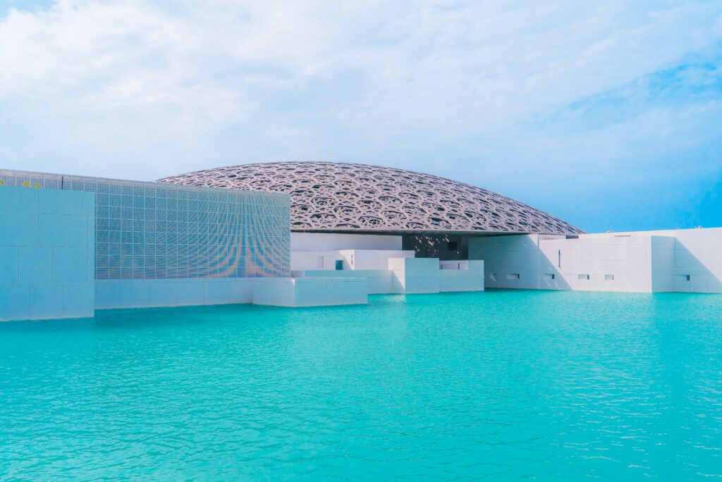 The domed Louvre Abu Dhabi on Saadiyat Island, rising from shallow turquoise water