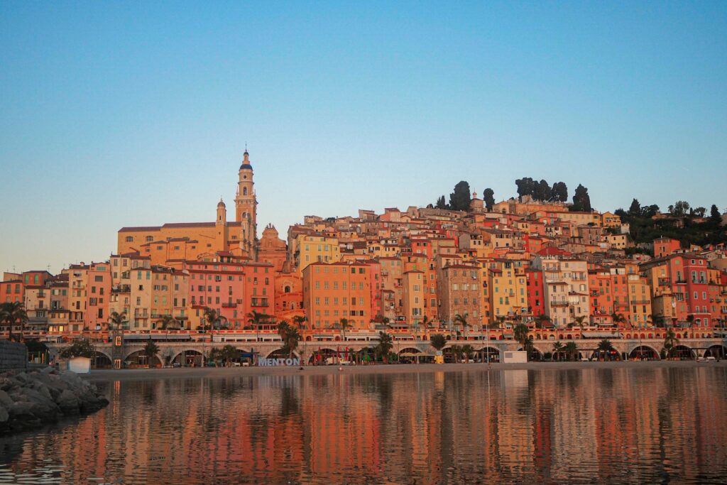 A pastel-coloured French Riviera waterfront town reflected in the harbour water