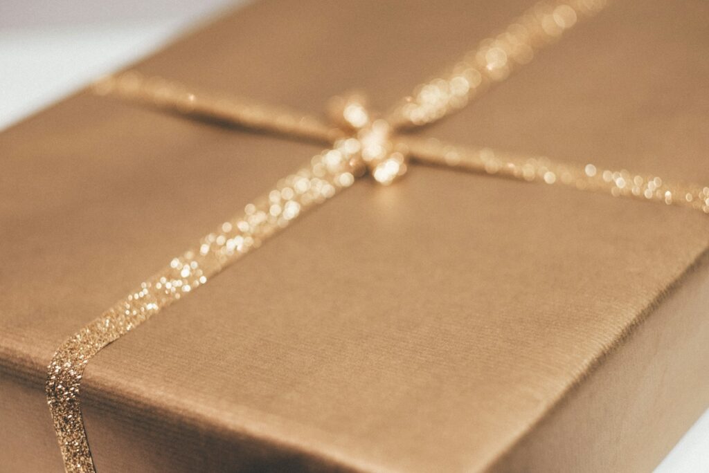 Close-up of a bronze-wrapped gift tied with a fine gold glitter ribbon.