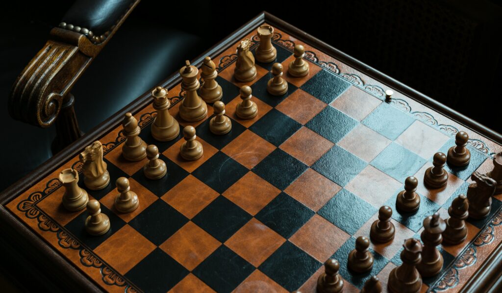 Leather chess board with wooden pieces beside a carved armchair, a classic among luxury gifts for men