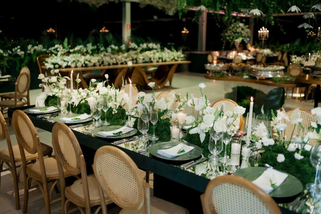 Wedding banquet table dressed with white flowers, candles, and place settings