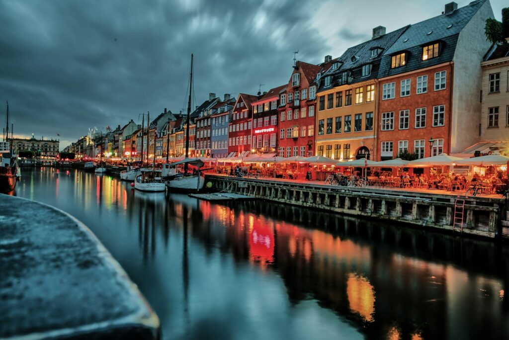 Nyhavn canal in Copenhagen at dusk with lit restaurant terraces