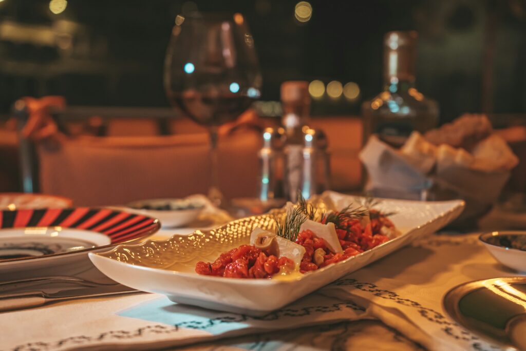 A table set for dinner in Florence, with a plated starter, a glass of red wine, and bread in warm evening light