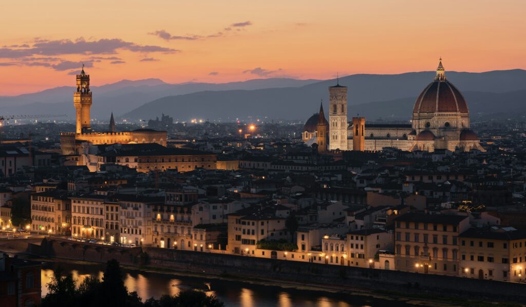 Michelin star restaurants Florence: the city skyline at dusk with the Duomo and a historic tower above the rooftops
