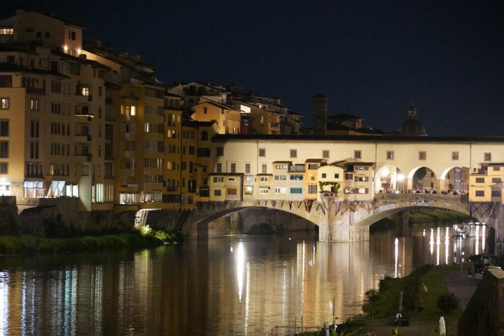 The Ponte Vecchio and the riverside buildings of Florence lit at night and reflected in the Arno