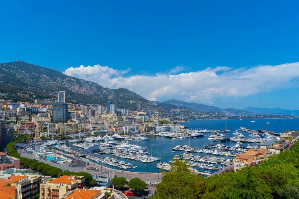 Port Hercule and the Monaco skyline under a blue sky, with yachts in the harbour