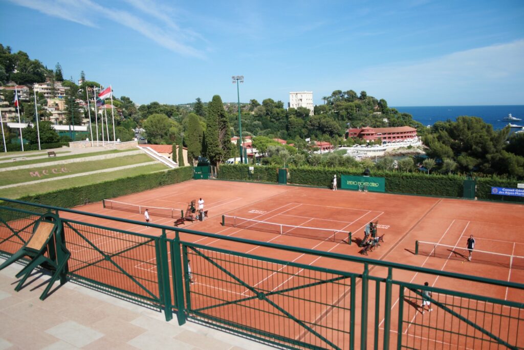 Clay courts at the Monte-Carlo Country Club with the sea beyond the trees