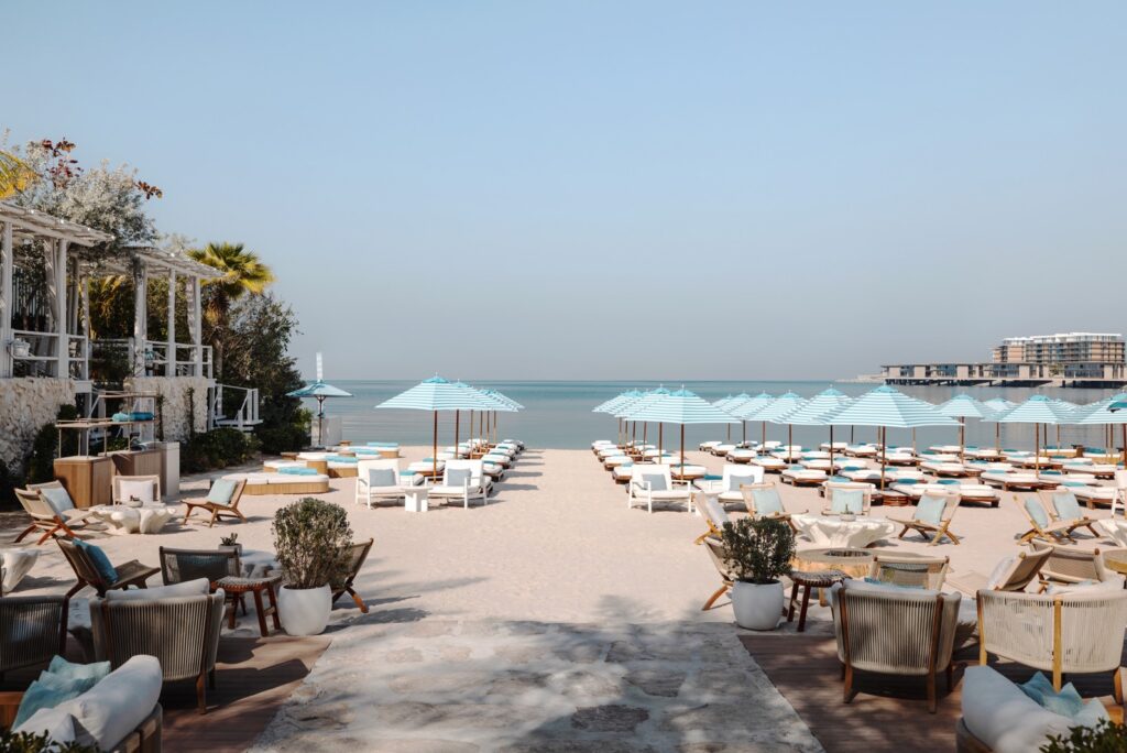 Striped umbrellas and sun loungers on the beach at Nammos Dubai, Four Seasons Jumeirah Beach